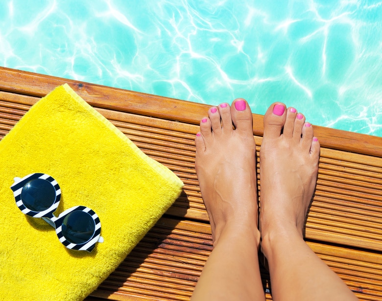 Summer holiday fashion selfie concept – woman on a wooden pier at the pool with summer accessories; sunglasses, towel pieds_piscine